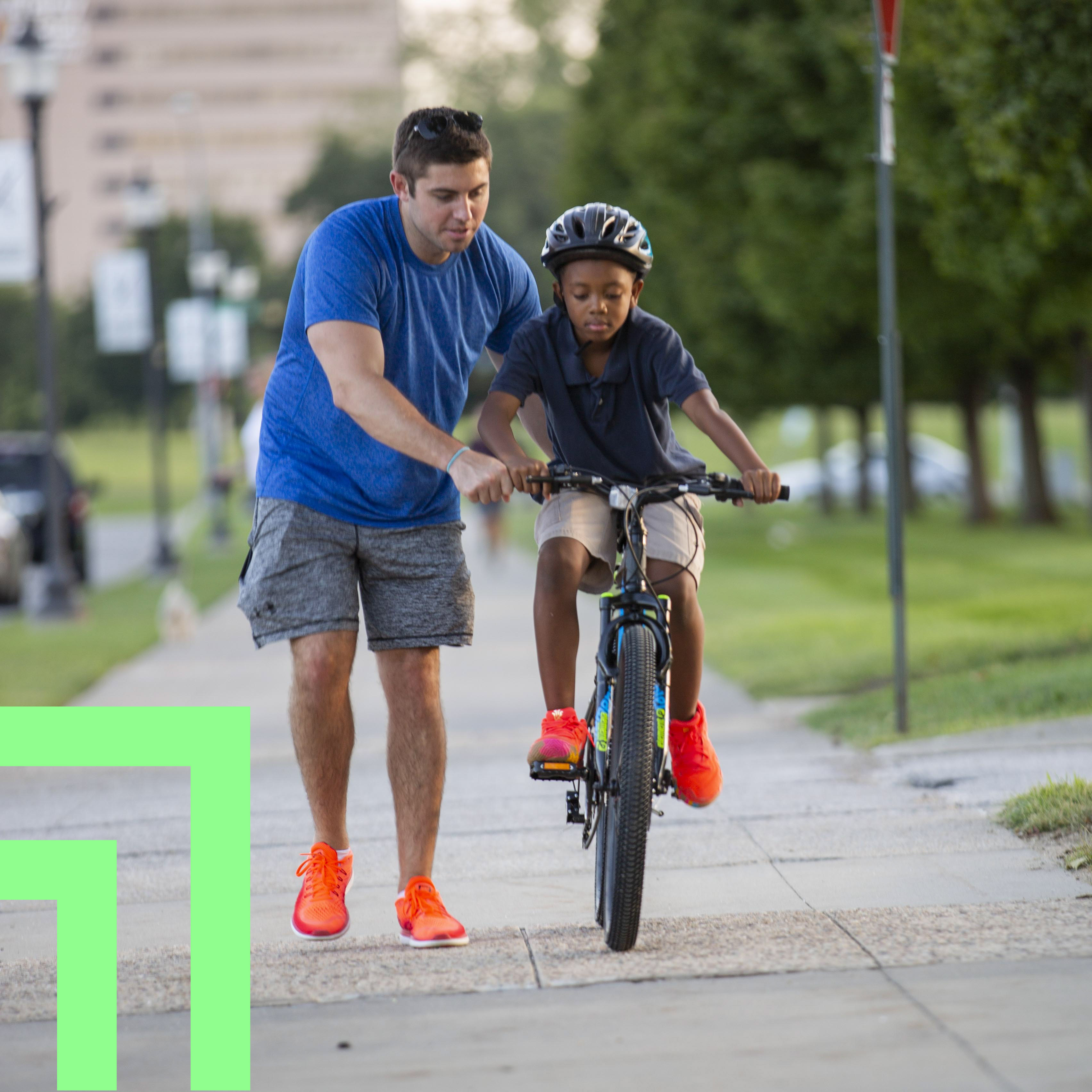 Big Brother helping Little Brother ride bike