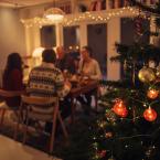 Family sitting at dinner table in background of a Christmas tree